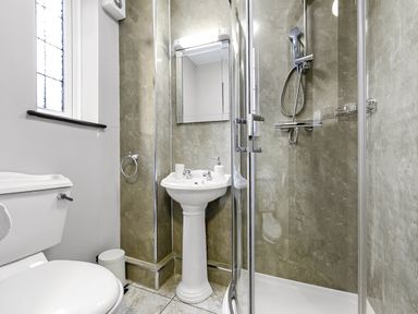 A bathroom with a toilet a pedestal sink a shower enclosure and a window at Tudor Grange in Bournemouth