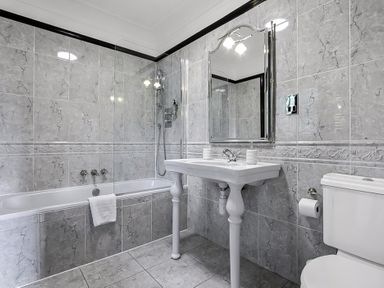 A bathroom with a bathtub shower sink mirror and toilet at Tudor Grange in Bournemouth