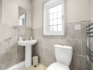 A bathroom with a pedestal sink mirror toilet window and a towel rack at Tudor Grange in Bournemouth