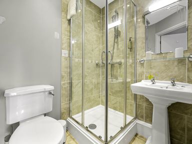 A bathroom with a toilet a glass shower enclosure and a pedestal sink at Tudor Grange in Bournemouth