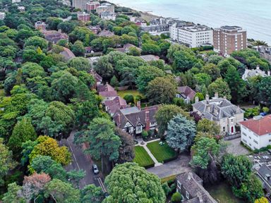 An aerial view of houses surrounded by trees near the coast at Tudor Grange in Bournemouth