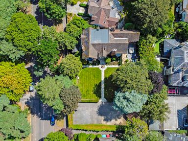 An aerial view of a residential house with a garden and driveway surrounded by trees at Tudor Grange in Bournemouth
