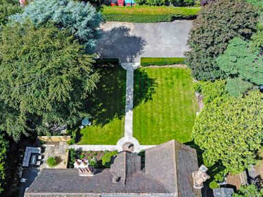 Aerial view of a garden with a lawn stone paths trees hedges and patio furniture at Tudor Grange in Bournemouth