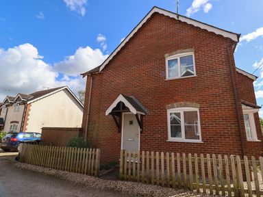 A brick house with white windows and a wooden fence outside at 8 Biddlecombe Orchard in Bridport