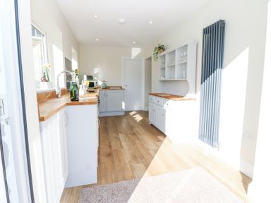 A kitchen with wooden countertops cabinets a radiator and a wooden floor at Bridge End Cottage in Wark