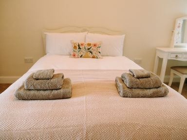 A bedroom with a neatly made bed with folded towels and a dressing table at Bridge End Cottage in Wark