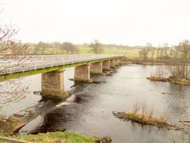 A bridge with stone pillars spanning a river in a rural area at Bridge End Cottage in Wark