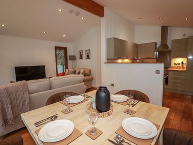 A dining table set for four with plates and glasses in an open plan living room and kitchen at 1 Streamside in Lanreath