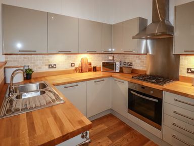 A kitchen with wooden countertops stainless steel sink and oven beige cabinets at 1 Streamside Lanreath