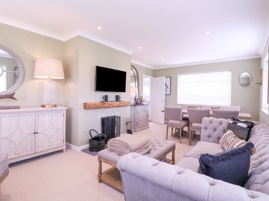 A living room with a gray sofa and a dining table with chairs in the background at The Farmhouse in St Osyth