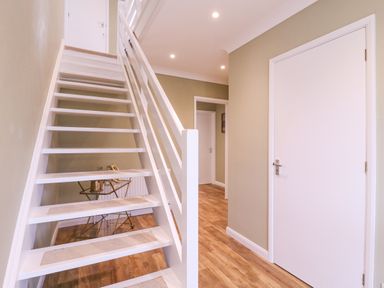 A hallway with white stairs and wooden flooring at The Farmhouse in St Osyth