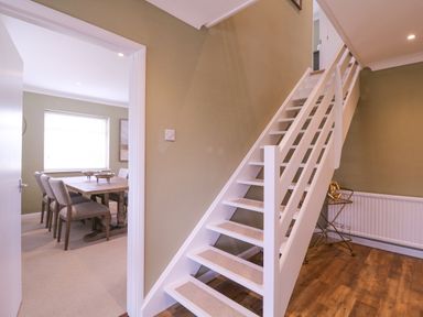 A staircase next to a dining area with chairs and a table at The Farmhouse in St Osyth