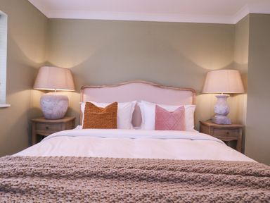 A bedroom with a bed with two textured pillows and two bedside tables with lamps at The Farmhouse in St Osyth
