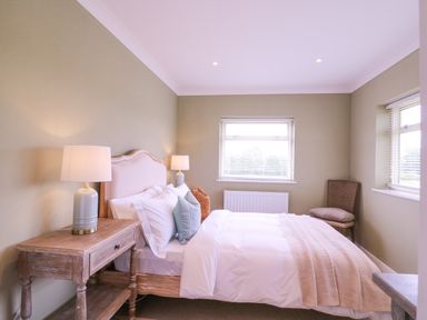 A bedroom with a bed pillows and lamps on bedside tables at The Farmhouse in St Osyth
