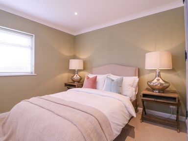 A bedroom with a bed with pillows and blankets and two bedside tables with lamps at The Farmhouse in St Osyth
