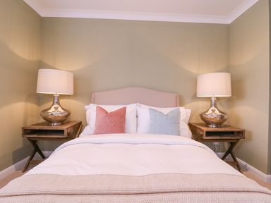 A bedroom with a bed that has white bedding and two pillows with wooden nightstands and table lamps on each side at The Farmhouse in St Osyth