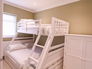 A bedroom with a white bunk bed and a white cabinet next to it at The Farmhouse in St Osyth