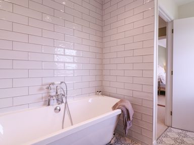 A bathroom with a white bathtub towel and tiled walls at The Farmhouse in St Osyth