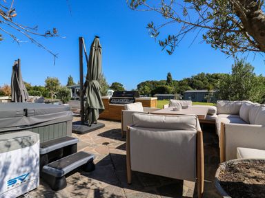 An outdoor seating area with hot tub and barbecue at The Farmhouse in St. Osyth