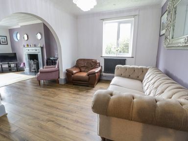 A living room with sofas armchairs and a fireplace at Tan Y Fron in Dyffryn Ardudwy
