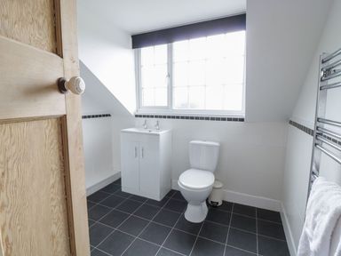 A bathroom with a toilet sink cabinet towel rail and window at Tan Y Fron in Dyffryn Ardudwy