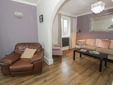 A living room with a brown leather armchair a beige sofa and a black coffee table at Tan Y Fron in Dyffryn Ardudwy