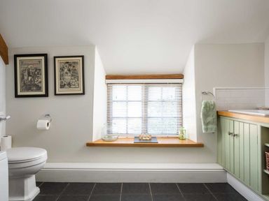 A bathroom with a toilet a window with blinds and a green cabinet at Hope Cottage in Longborough