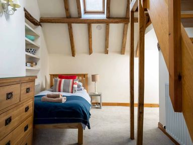 A bedroom with a single bed a chest of drawers and wooden beams on the ceiling at Hope Cottage in Longborough