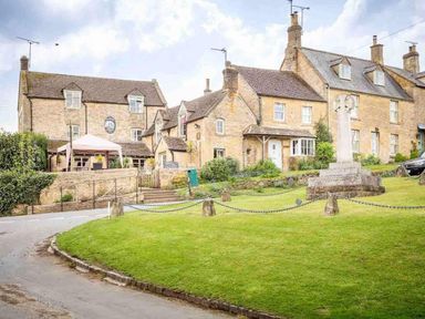 A village street with stone houses a grassy area with a monument and a road at Hope Cottage in Longborough