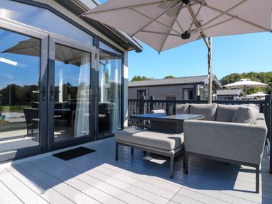 An outdoor terrace with furniture and an umbrella at Lakewood Plot 2 St. Osyth