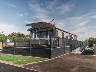 A house with a deck and umbrella at Lakewood Plot 2 St. Osyth