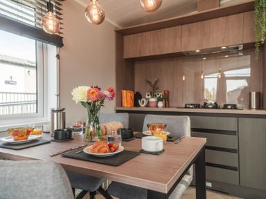 A dining room setup with a table, kitchen appliances, and a flower vase at Lakewood Plot 2 St. Osyth