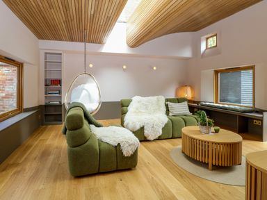 A living room with green sofas wooden ceiling hanging chair and wooden coffee table at Oak Cottage in Somerleyton