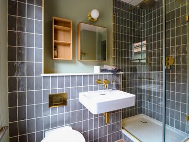 A bathroom with a wall-mounted sink shower area and toilet at Oak Cottage in Somerleyton