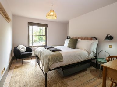 A bedroom with a bed a chair a desk and a window at Oak Cottage in Somerleyton