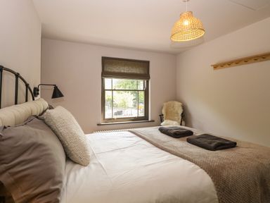 A bedroom with a bed pillows folded towels window chair and wall hanger at Oak Cottage in Somerleyton