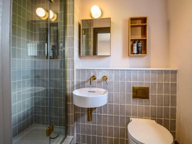 A bathroom with a glass shower enclosure a wall-mounted sink and a toilet at Oak Cottage in Somerleyton