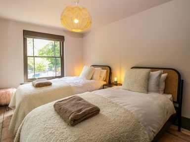 A bedroom with two single beds each with cream blankets and bath towels on the beds at Oak Cottage in Somerleyton