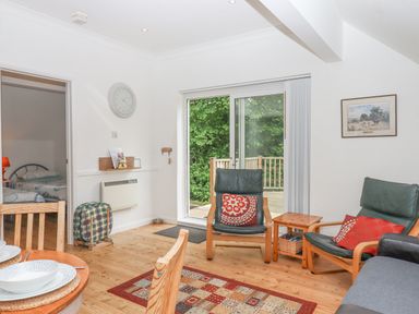 A living room with wooden floor chairs and a sliding glass door leading outside at Crystals Hatherleigh