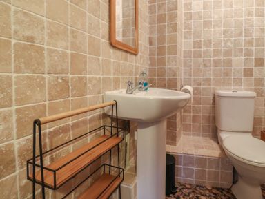 A bathroom with a pedestal sink mirror toilet wooden and metal shelf at Butterton Cottage in Combe Raleigh near Honiton