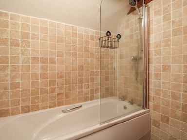 A bathroom with a bathtub shower and tiled walls at Butterton Cottage in Combe Raleigh near Honiton