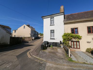 A street with houses and a driveway under a blue sky at The Nook in Brixham
