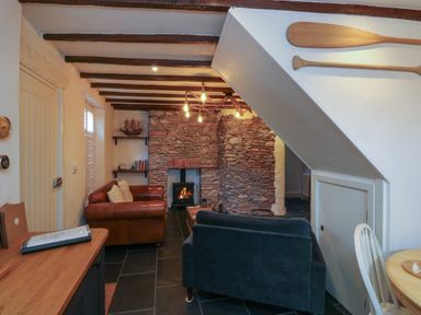 A living room with a stone fireplace two sofas wooden paddles on the wall and a wooden table at The Nook in Brixham