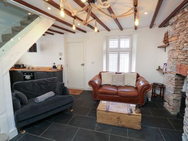A living room with two sofas a wooden chest coffee table exposed beams and a kitchen corner at The Nook in Brixham