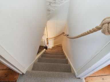 A carpeted staircase with a rope handrail and white walls at The Nook in Brixham