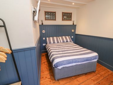 A bedroom with a double bed striped bedding blue wainscoting and wooden floor at The Nook in Brixham