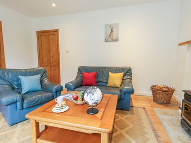 A living room with two blue leather sofas and a coffee table with fruit and a globe at Coldharbour Farm Bungalow Annexe Coldharbour near Wareham