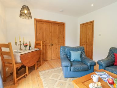 A sitting room with blue leather armchairs wooden dining table and wooden doors at Coldharbour Farm Bungalow Annexe Coldharbour near Wareham