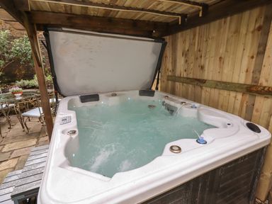 An outdoor covered area with a hot tub and patio furniture at The Old Sorting Office in Hawarden