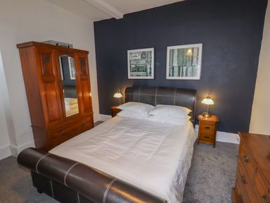 A bedroom with a bed two bedside tables and a wardrobe at The Old Sorting Office in Hawarden